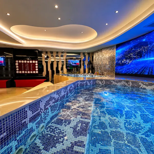 Large blue-lit bath pool with stage backdrop