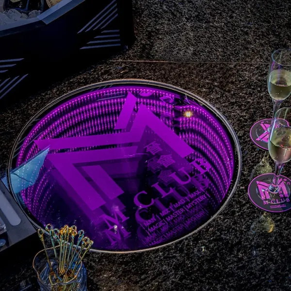 Purple-lit round table with M Club floor logo